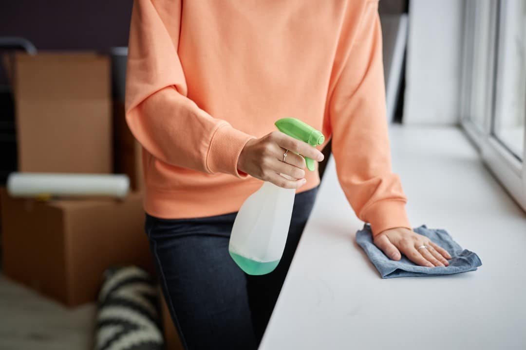 Person disinfecting and wiping a tabletop with cloth, ensuring high-quality deep cleaning and hygiene.