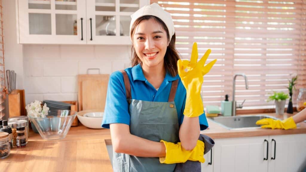 rofessional maid service cleaner smiling in a spotless kitchen during a residential deep cleaning session.